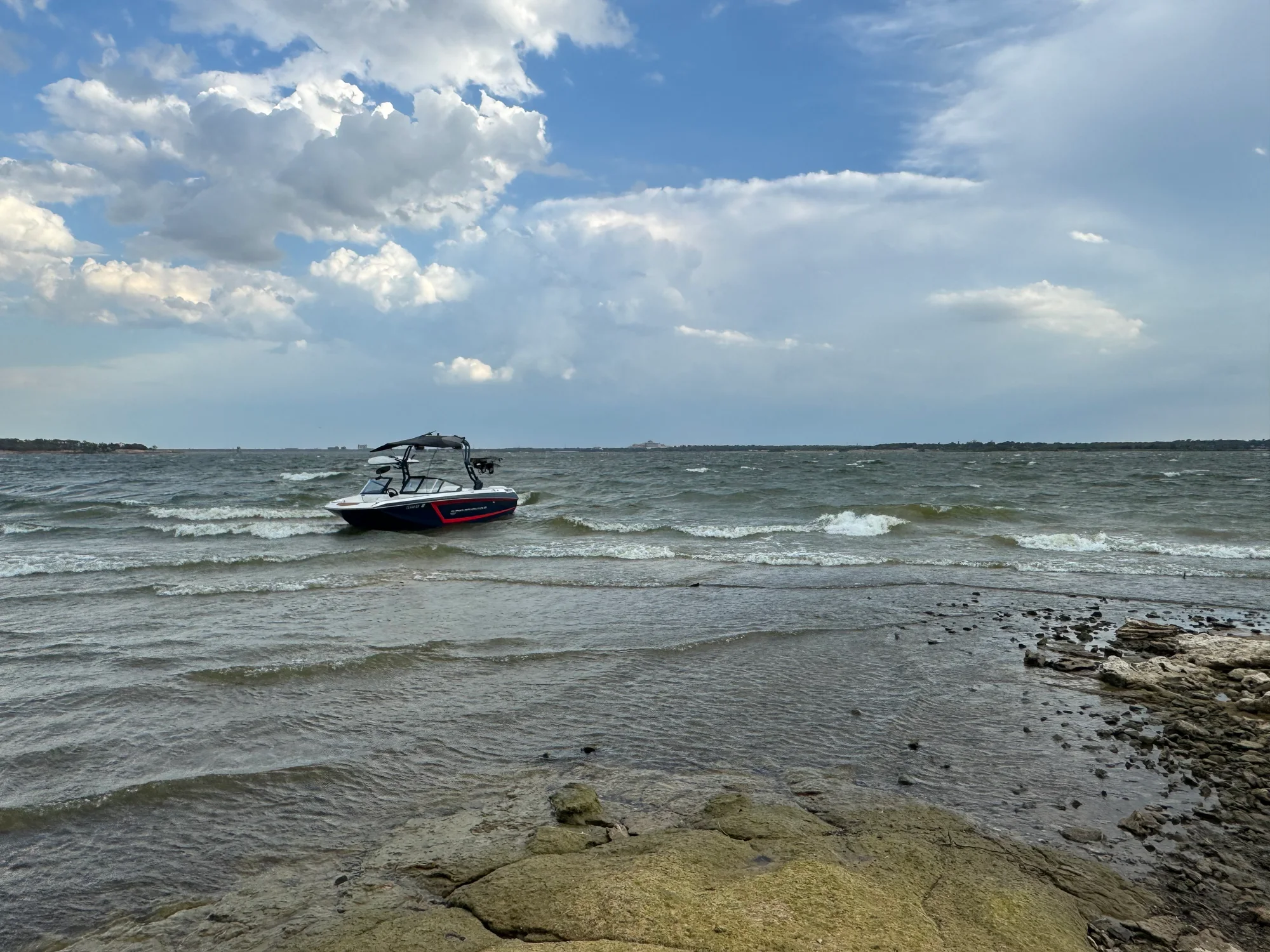 A boat on the water at Lake Ray Hubbard, near a rocky shoreline